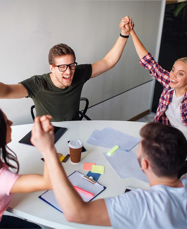 Desilo startup team celebrating collaboration and MVP success with a group of founders holding hands around a table